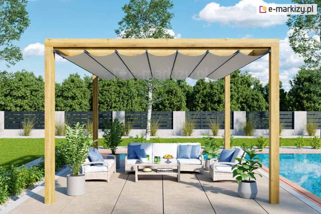 Pergola tarasowa drewniana juko wolnostojąca na tarasie przy basenie, dach rzymski chroni jasne meble z błękitnymi poduszkami przed promieniowaniem słonecznym.