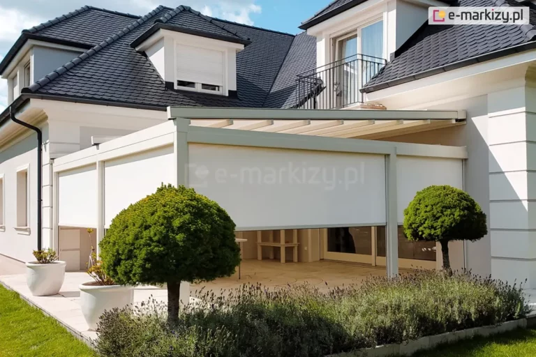 Nowoczesny piętrowy budynek mieszkalny o białej elewacji i grafitowym dachu z dużym tarasem w narożniku, osłoniętym pergolą z roletami screen ZIP L ZIP U. Całość została dopasowana kolorystycznie do elewacji budynku. Przed tarasem zadbany kwietnik z polem lawendy oraz dwoma niskimi drzewami. Przy zejściu z tarasu na trawnik ustawiono dwie duże białe donice z kwiatami.