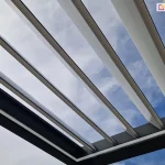 Konstrukcja pergoli tarasowej przyściennej z otwartym dachem z uchylonych lameli w pozycji skośnej oraz oświetleniem led na wewnętrznej stronie ramy