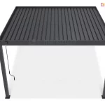 Nowoczesna pergola tarasowa z dachem lamelowym sterowanym ręcznie przedstawiona na jednolitym białym tle. Całość konstrukcji, obejmująca cztery pionowe słupy nośne oraz ramę zadaszenia, wykonana jest z aluminium w głębokim, matowym odcieniu ciemnej szarości lub antracytu. Zadaszenie składa się z równolegle ułożonych, podłużnych lameli, które tworzą szczelną, żebrowaną płaszczyznę dachową. Lamele są osadzone wewnątrz solidnej, prostokątnej ramy. Na przednim lewym słupie, tuż pod górną belką, zamontowany jest mechanizm sterujący w formie zwisającej, czarnej korby z rączką, służącej do manualnej regulacji kąta nachylenia piór dachu. Słupy wspierające mają kwadratowy przekrój i są zakończone u dołu płaskimi stopami montażowymi, które stabilizują konstrukcję na podłożu. Perspektywa ujęcia ukazuje produkt z lekkiego podwyższenia, co pozwala dokładnie przyjrzeć się strukturze zamkniętego dachu oraz proporcjom całej wolnostojącej budowli ogrodowej.