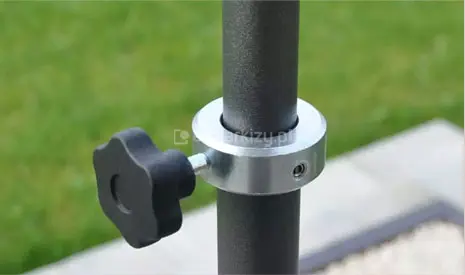 Widok na element stabilizujący konstrukcję markizy tarasowej, przedstawiający obejmę zaciskową z pokrętłem blokującym, która pozwala na płynną regulację wysokości oraz pewne unieruchomienie teleskopowego profilu wsporczego.