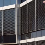 Oszklony budynek osłonięty żaluzjami fasadowymi z kasetą oval zamontowanymi modułowo.