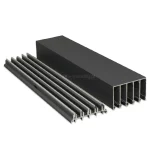 Zdjęcie prezentuje dwa antracytowe profile aluminiowe z matowym wykończeniem, które tworzą 5-torowy system przesuwny Auris do zabudowy tarasowej. Po prawej stronie znajduje się wysoka prowadnica górna z pięcioma pionowymi komorami, natomiast po lewej stronie widoczna jest niska prowadnica dolna wyposażona w pięć wypukłych szyn jezdnych. Elementy są ułożone równolegle pod skosem na jasnym tle, co pozwala na dokładne zaobserwowanie ich wielotorowej konstrukcji oraz precyzyjnie wyprofilowanych krawędzi. Całość stanowi kompletny zestaw montażowy umożliwiający płynne przemieszczanie pięciu skrzydeł drzwi przesuwnych.