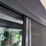 Górny profil moskitiery Click Rol stanowi ukrytą prowadnicę, w której porusza się profil z siatką oraz gąsienice. Moskitiera z antracytową konstrukcją zamocowana na oknie w tej samej kolorystyce.