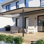 Grafitowa pergola z beżową tkaniną pasuje kolorystycznie do nowoczesnego tarasu