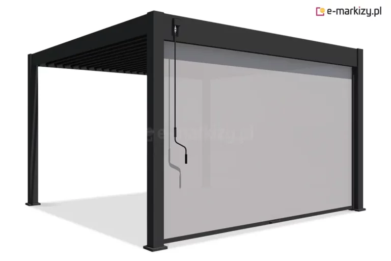 Wizualizacja nowoczesnej pergoli lamelowej Marlo w kolorze antracytowym, wyposażonej w szeroką roletę przednią typu screen. Konstrukcja o prostopadłościennej formie posiada dach z ruchomymi lamelami oraz cztery masywne nogi o kwadratowym przekroju. Na dłuższym boku pergoli zamontowano pionową osłonę przeciwsłoneczną w kolorze jasnoszarym, która jest niemal całkowicie rozwinięta, osłaniając wnętrze przed słońcem i wiatrem. Tkanina rolety charakteryzuje się delikatną przeziernością, a w jej dolnej części widoczny jest ergonomiczny uchwyt. Przy górnej ramie, po lewej stronie frontu, umocowana jest długa, czarna korba ręczna służąca do manualnego sterowania kątem nachylenia lameli dachowych. Całość przedstawiona jest z perspektywy bocznej na białym, neutralnym tle, co podkreśla techniczne walory i estetykę wykończenia produktu.