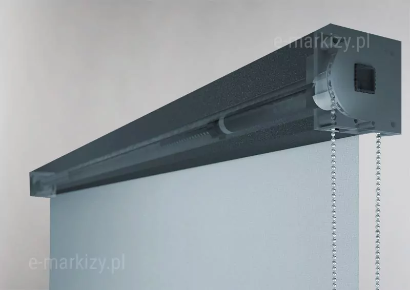 Trójwymiarowa wizualizacja techniczna ukazująca wewnętrzny mechanizm sterujący systemu refleksol 85MA Aluprof w dużym przybliżeniu. Zdjęcie prezentuje przekrój boczny kasety o barwie ciemnego antracytu z matowym wykończeniem, w której boczna i frontowa ścianka zostały przedstawione jako półprzezroczyste, aby odsłonić detale konstrukcyjne. Wewnątrz obudowy widoczny jest mechanizm napędowy z kołem zębatym, przez które przewieszony jest srebrny łańcuszek kulkowy służący do ręcznej obsługi rolety. Łańcuszek zwisa pionowo w dół przez otwór w dolnej części kasety. Z mechanizmu wyprowadzona jest rura nawojowa, na którą nawinięta jest jasnoszara tkanina techniczna ekranu. Konstrukcja mechanizmu jest precyzyjnie dopasowana do kwadratowego profilu kasety, a boczny dekiel posiada widoczne otwory na śruby montażowe. Całość ukazana jest na neutralnym, jasnym tle, co podkreśla techniczny charakter detalu i precyzję wykonania elementów sterujących systemu refleksol 85MA.