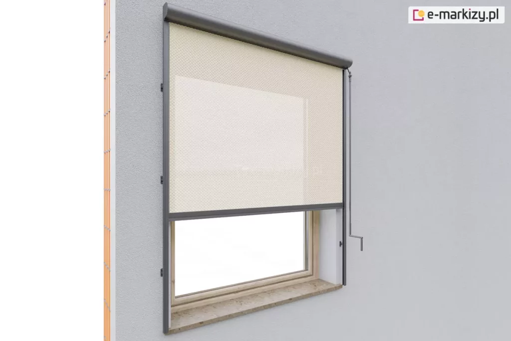 Nowoczesna osłona okna - Refleksol 90 Selt zamontowany nad niewielkim oknem z parapetem z kamienia naturalnego, osadzonym w ścianie w kolorze jasnoszarym. Osłona wykonana z półprzezroczystej tkaniny o ciepłym, piaskowym odcieniu została częściowo rozwinięta – zasłania górną połowę przeszklenia, pozostawiając dolną część odsłoniętą. Tkanina prowadzona jest przez belkę dolna osadzona w prowadnicach bocznych, przykręconych do ściany elewacji poza wnęka okienną za pomocą uchwytów, co zabezpiecza ją przed falowaniem i pozwala utrzymać jej napięcie. Górna kaseta, o łagodnie zaokrąglonym kształcie, została zaprojektowana z myślą o dyskretnej estetyce oraz funkcjonalności – chroni mechanizm rolety przed wpływem warunków atmosferycznych. Z prawej strony kasety widoczna korba do ręcznego zwijania i rozwijania osłony.