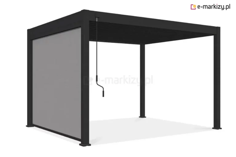 Wizualizacja nowoczesnej pergoli lamelowej Marlo w kolorze ciemnego grafitu lub antracytu, wyposażonej w funkcjonalną roletę boczną. Konstrukcja pergoli opiera się na czterech solidnych, kwadratowych słupach podtrzymujących płaski dach z ruchomymi lamelami. Na jednym z boków zamontowano pionową roletę przeciwsłoneczną w kolorze jasnoszarym, która jest częściowo rozwinięta, zakrywając około dwie trzecie wysokości prześwitu między słupami. Tkanina rolety ma drobną, siatkowatą strukturę typu screen, zapewniającą ochronę przed słońcem i wiatrem przy jednoczesnym zachowaniu częściowej przezierności. Do obsługi mechanizmu dachowego służy długa, czarna korba ręczna z profilowanym uchwytem, zwisająca z górnej belki konstrukcyjnej. Całość została zaprezentowana na jednolitym, białym tle z delikatnym cieniem rzucanym przez konstrukcję na podłoże, co podkreśla techniczne detale produktu.