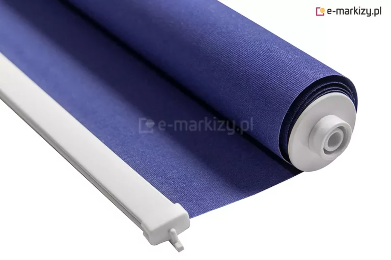 Roletka mini z białym mechanizmem i niebieską tkaniną bez mocowań, ułożona z częściowo wysunięta z rurki nawojowej tkaniną i widocznym aluminiowym obciążnikiem. Całość zaprezentowana na białym tle.