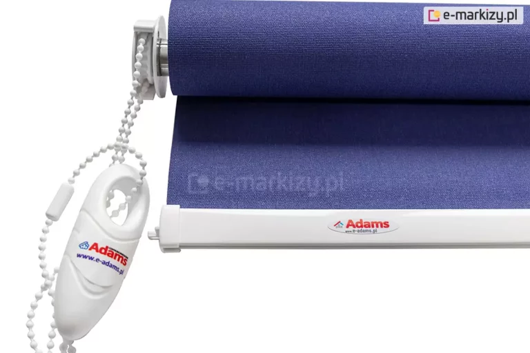 Widok na bok rolety mini z widocznym połączeniem mechanizmu łańcuszkowego z rurą nawojową tkaniny. Białe elementy wykończenia rolety (obciążnik tkaniny, łańcuszek, mechanizm) doskonale wyglądają w połączeniu z niebieską tkaniną roletki.
