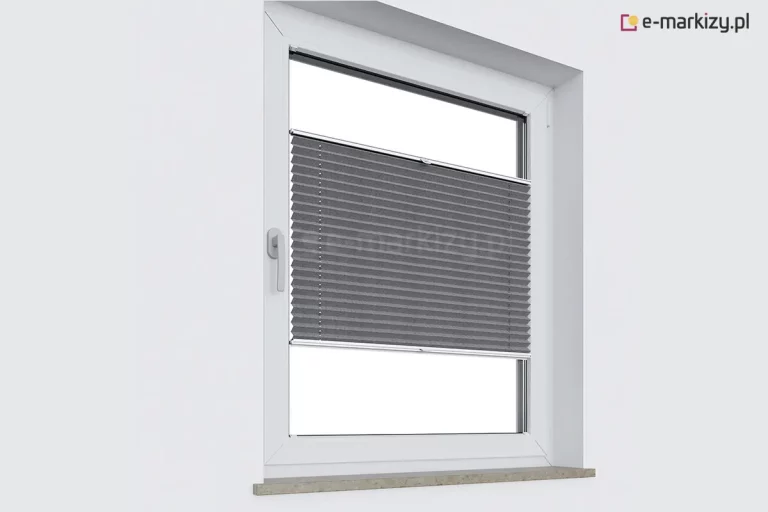Zdjęcie prezentuje białe, jednoskrzydłowe okno osadzone w gładkiej, jasnej ścianie, na którym zamontowana została nowoczesna plisa okienna w kolorze ciemnoszarym lub grafitowym. Plisa okienna jest ustawiona w pozycji środkowej, co oznacza, że zasłania centralną część szyby, pozostawiając wolną przestrzeń zarówno u góry, jak i u dołu okna. Tkanina osłony posiada charakterystyczne, gęste i regularne poziome plisowania, które układają się w strukturę harmonijki. Konstrukcja opiera się na dwóch ruchomych profilach aluminiowych w kolorze białym – górnym i dolnym – z których każdy wyposażony jest w centralnie umieszczony uchwyt do sterowania. Dzięki systemowi sznurkowemu, plisy okienne tego typu pozwalają na dowolne przesuwanie materiału po całej wysokości światła szyby. Okno posiada białą klamkę umieszczoną po lewej stronie oraz wąski, kamienny lub kompozytowy parapet o nakrapianej strukturze w odcieniach beżu i szarości. Całość kompozycji ukazuje funkcjonalność i estetykę plisy okiennej jako elementu dekoracyjnego i ochronnego, który idealnie przylega do ramy okiennej, nie ograniczając dostępu do klamki.