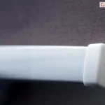 Zbliżenie aluminiowego obciążnika z zaślepką z PCV w kolorze białym do rolety wolnowiszącej PLUS z brązową tkaniną.