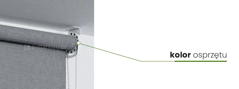 Uchwyt mocujący roletę wolnowiszącą PLUS do sufitu w kolorze białym z białym łańcuszkiem oraz nawinięta na rurkę nawojowa szara tkanina po lewej stronie. Od uchwytu oznaczonego białym kółeczkiem w zielonej ramce poprowadzona w prawo linia, pogrubiona pod napisem "kolor osprzętu".