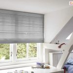 Rolety rzymskie do biura lub domowej pracowni z półprzezierną szarą tkaniną osłaniającą przed nadmiernym nasłonecznieniem, ale nie ograniczającą światła