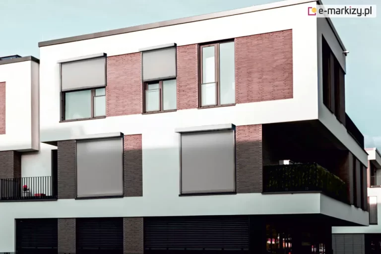 Dwupiętrowy budynek mieszkalny wielorodzinny z oknami osłoniętymi roletami ZIP L. Okna pierwszego pięta przesłonięte zostały całkowicie, dwa okna na drugim piętrze po lewej zasłonięte są do połowy, a trzecie okno - po prawej stronie nie posiada zamocowanej rolety screen.