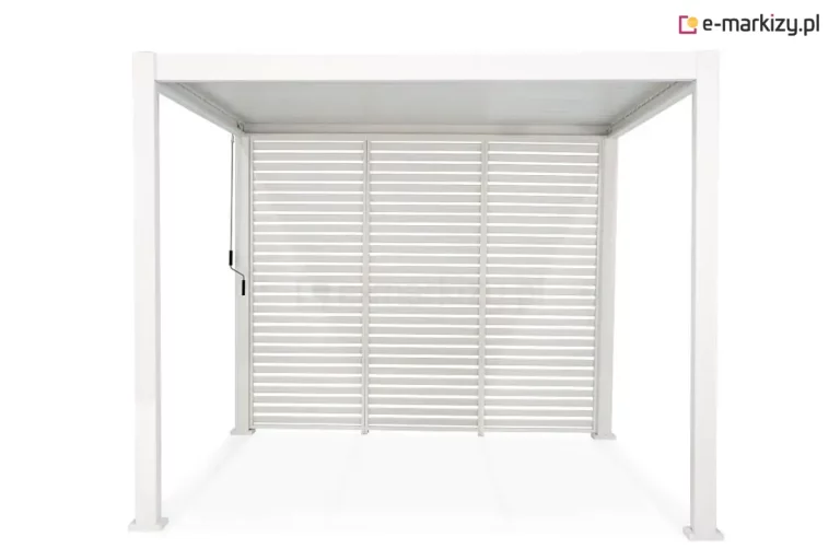 Biała pergola ogrodowa Gloria z pełną zabudową tylnej ściany wykonaną z trzech stałych paneli żaluzjowych. Panele są zamontowane obok siebie, wypełniając całkowicie przestrzeń między dwoma tylnymi słupami konstrukcji. Każdy moduł składa się z poziomych, równolegle ułożonych lameli aluminiowych w kolorze białym, które tworzą spójną barierę wizualną, przepuszczając jednocześnie powietrze. Cała konstrukcja, włączając cztery pionowe słupy z kwadratowymi podstawami oraz ramy paneli, jest wykończona w jednolitym białym kolorze. Po lewej stronie, przy przednim słupie, widoczny jest pionowy drążek mechanizmu korbowego do regulacji zadaszenia. Wnętrze pergoli jest puste, a podłoże oraz tło są jasne i jednolite.
