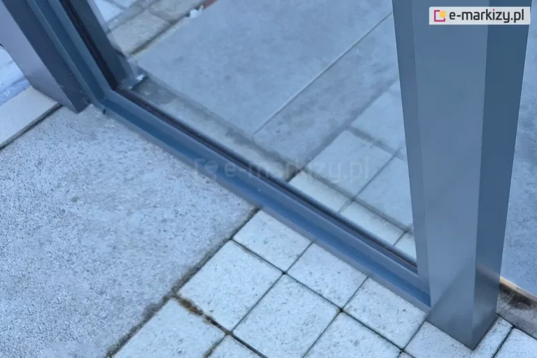 Stała ściana szklana okno do zadaszenia tarasu Fest, zamocowane do aluminiowej konstrukcji zadaszenia oraz podłoża z kostki brukowej.