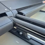 Zbliżenie uchwytu modułowego systemu veranda Selt, w którym zamocowane są dwie prowadnice oraz kasety w kolorze antracytu. W jednej z prowadnic widoczna linka odpowiadająca za prawidłowe naprężenie tkaniny rolety poziomej.