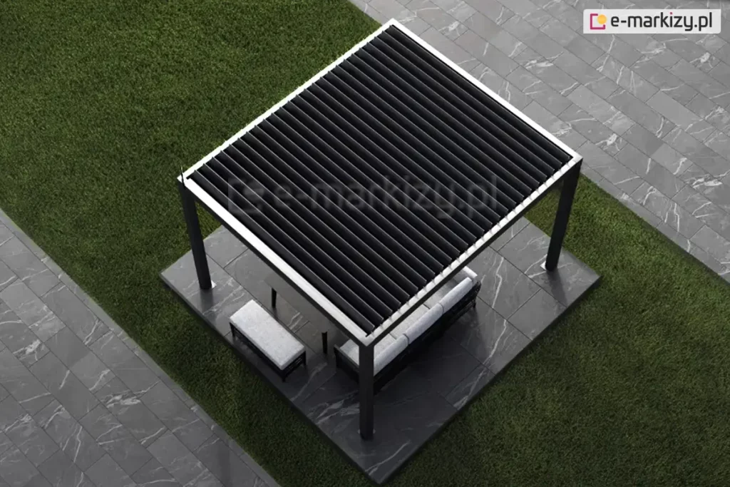 Widok z góry na nowoczesną pergolę tarasową SB350 o konstrukcji wolnostojącej, umieszczoną na kwadratowym podeście z ciemnoszarych płyt tarasowych o strukturze marmuru. Rama pergoli wykonana jest z metalu w kolorze antracytowym z jasnymi, srebrzystymi krawędziami górnego profilu. Zadaszenie składa się z ruchomych lameli (bioklimatycznych) w kolorze czarnym, które są ustawione w pozycji lekko uchylonej. Pod pergolą znajduje się zestaw mebli ogrodowych: jasnoszara sofa z oparciem oraz dopasowana kolorystycznie niska ława. Konstrukcja stoi na zielonym, równo przystrzyżonym trawniku, a obok przebiega ścieżka wykonana z tych samych ciemnych płyt wielkoformatowych co podest.