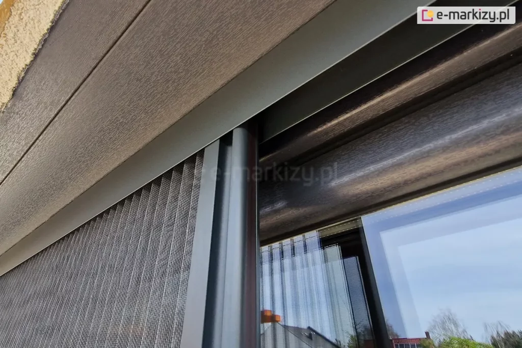 Moskitiera plisowana Top Zag zamontowana we wnęce okiennej tuż przy ramie oknie o antracytowym kolorze, pakiet z plisowaną siatką przesuwa się wewnątrz profilu górnego, co zapewnia jeszcze lepszą ochronę przed owadami.