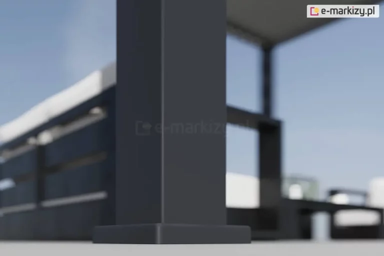 Zbliżenie na dolną część pionowej podpory (słupa) pergoli bioklimatycznej Rubio w kolorze antracytowym. Zdjęcie prezentuje wzmocnioną stopę montażową o kwadratowym przekroju, która jest osadzona bezpośrednio na jasnej, płaskiej nawierzchni tarasu. Konstrukcja słupa posiada gładkie, matowe wykończenie i charakteryzuje się masywnym profilem zapewniającym stabilność całej budowli. W tle, na rozmytym planie, widoczne są elementy wyposażenia tarasu: fragmenty ciemnych mebli ogrodowych z białymi poduszkami oraz boczna przesłona pergoli. Całość scenerii dopełnia jasne, dzienne światło i błękitne niebo, co podkreśla nowoczesny design produktu oraz jego integrację z otwartą przestrzenią wypoczynkową.