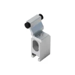 Zdjęcie prezentuje pojedynczy element techniczny wykonany z metalu w kolorze srebrnym, stanowiący zabierak do paneli w systemie przesuwnym Auris. Komponent ma zwartą, geometryczną budowę z pionowym korpusem, w którym widoczny jest owalny otwór montażowy oraz precyzyjnie wyfrezowane wpusty w dolnej części. Górna sekcja zabieraka jest odgięta pod kątem i zakończona poprzecznym bolcem, na którego końcach osadzono dwa czarne, gumowe odbojniki o cylindrycznym kształcie. Element przedstawiony jest w rzucie izometrycznym na białym tle, co uwidacznia gładką powierzchnię metalu oraz detale konstrukcyjne odpowiedzialne za stabilne zahaczanie i ciche przesuwanie kolejnych tafli szkła w wielotorowej prowadnicy.