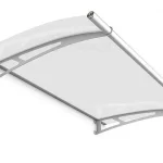 Produktowa wizualizacja prezentuje nowoczesne zadaszenie drzwiowe z serii Elegant w wersji z wypełnieniem satynowym. Konstrukcja składa się z półprzezroczystej płyty o mlecznym wykończeniu, która jest osadzona na dwóch srebrnych, stalowych wspornikach o łukowatym kształcie. Wsporniki posiadają charakterystyczne, geometryczne wycięcia o ażurowym charakterze, co nadaje całości lekkości wizualnej. Na przedniej krawędzi daszka znajduje się zintegrowana, aluminiowa rynienka odpływowa o okrągłym przekroju, zakończona dopasowaną kolorystycznie zaślepką. Górna część zadaszenia, przylegająca do ściany, wykończona jest estetycznym profilem montażowym. Całość jest przedstawiona pod kątem na białym tle, co podkreśla nowoczesny design i funkcjonalny kształt produktu.