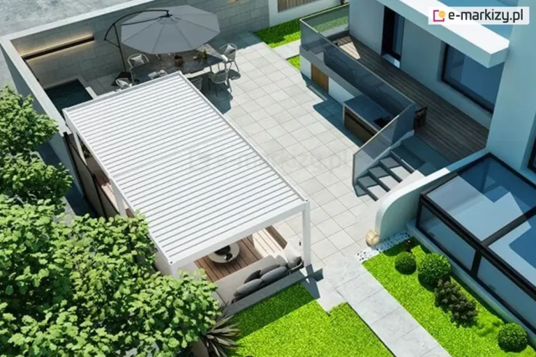 Widok z lotu ptaka na nowoczesny taras i ogród, w którego centralnej części znajduje się biała pergola wolnostojąca o wymiarach 600 na 300 centymetrów z dachem wykonanym z ruchomych lameli ustawionych w pozycji zamkniętej. Pod zadaszeniem umiejscowiona jest strefa wypoczynkowa z szarą kanapą narożną i niskim stolikiem kawowym na drewnianym podeście. Całość tarasu wyłożona jest jasnoszarymi płytami wielkoformatowymi. W głębi posesji widoczna jest jadalnia pod gołym niebem ze stołem, krzesłami oraz dużym rozłożonym parasolem przeciwsłonecznym w kolorze szarym. Architektura budynku jest minimalistyczna, o białej elewacji z dużymi przeszkleniami oraz zewnętrznymi schodami prowadzącymi na wyższy poziom. Wzdłuż tarasu rozciąga się pas zieleni z przystrzyżonym trawnikiem i ozdobnymi krzewami w formie kul. Po lewej stronie kompozycję domykają korony drzew liściastych rzucające cień na fragment nawierzchni.