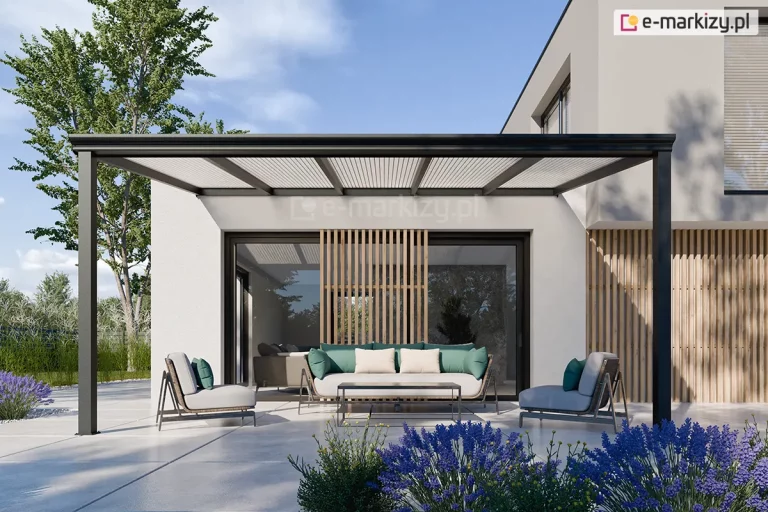 Frontowe ujęcie nowoczesnego zadaszenia tarasowego Lunaro o konstrukcji w kolorze głębokiego antracytu, zamontowanego do jasnej elewacji piętrowego budynku o minimalistycznej bryle. Lekko nachylony dach wypełniony jest panelami z poliwęglanu komorowego o prążkowanej strukturze, które są podtrzymywane przez smukłe krokwie. Całość opiera się na dwóch kwadratowych słupach nośnych, tworząc otwartą i przestronną strefę wypoczynku na jasnym, betonowym tarasie. Pod zadaszeniem znajduje się elegancki zestaw mebli ogrodowych, składający się z długiej sofy z zielono-beżowymi poduszkami, dwóch dopasowanych foteli oraz prostego, czarnego stolika kawowego. Przeszklenia budynku są częściowo osłonięte pionowymi, drewnianymi lamelami, które stanowią element dekoracyjny elewacji. Aranżację dopełniają kępy fioletowej lawendy posadzone na pierwszym planie oraz widok na wysokie drzewa liściaste i błękitne niebo w tle.