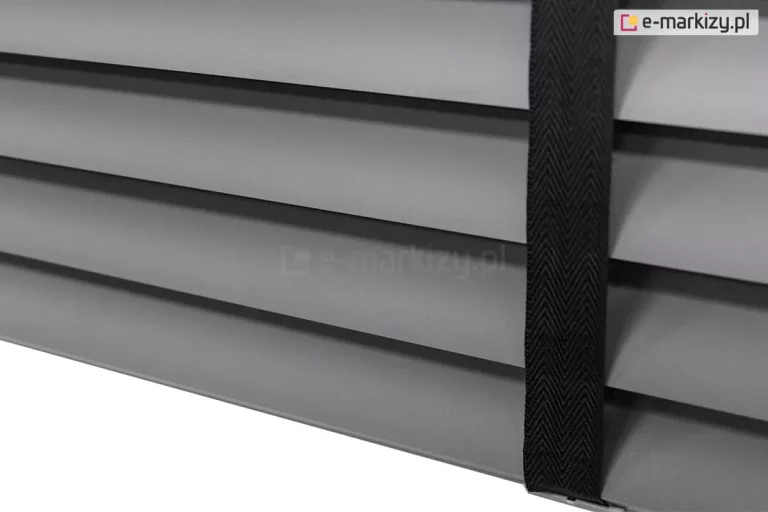Żaluzja aluminiowa z lamelami 50 mm w kolorze szarym o matowym wykończeniu, której elegancję podkreśla drabinka taśmowa w kolorze czarnym.