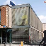 Żaluzje fasadowe Z90 Oval jako osłona pojedyncza i modułowa na budynku dużego biurowca, przed którym ustawiono kartonowe wizerunki tancerzy