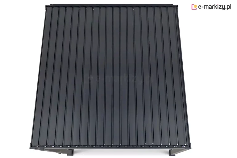 Widok z góry na dach bioklimatycznej pergoli tarasowej w kolorze antracytowym. Konstrukcja przedstawiona jest na czystym, białym tle, ukazując precyzyjny układ szczelnie zamkniętych lamel aluminiowych. Płaska powierzchnia dachu składa się z licznych, równoległych paneli o matowym wykończeniu, które tworzą jednolitą i nieprzepuszczalną osłonę. W dolnej części kadru widoczne są jedynie górne fragmenty czterech pionowych słupów nośnych oraz krawędź ramy konstrukcyjnej. Perspektywa z lotu ptaka podkreśla minimalistyczny, geometryczny design zadaszenia oraz wysoką jakość spasowania elementów mechanizmu ruchomego dachu.