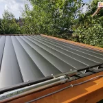 Dach lamelowy SB400 MD z zamkniętymi lamelami w kolorze antracytowym, na pierwszym planie widoczny silnik, kabel zasilający przymocowany do drewnianej belki konstrukcji pergoli oraz mechanizm sterujący ruchem lamel.