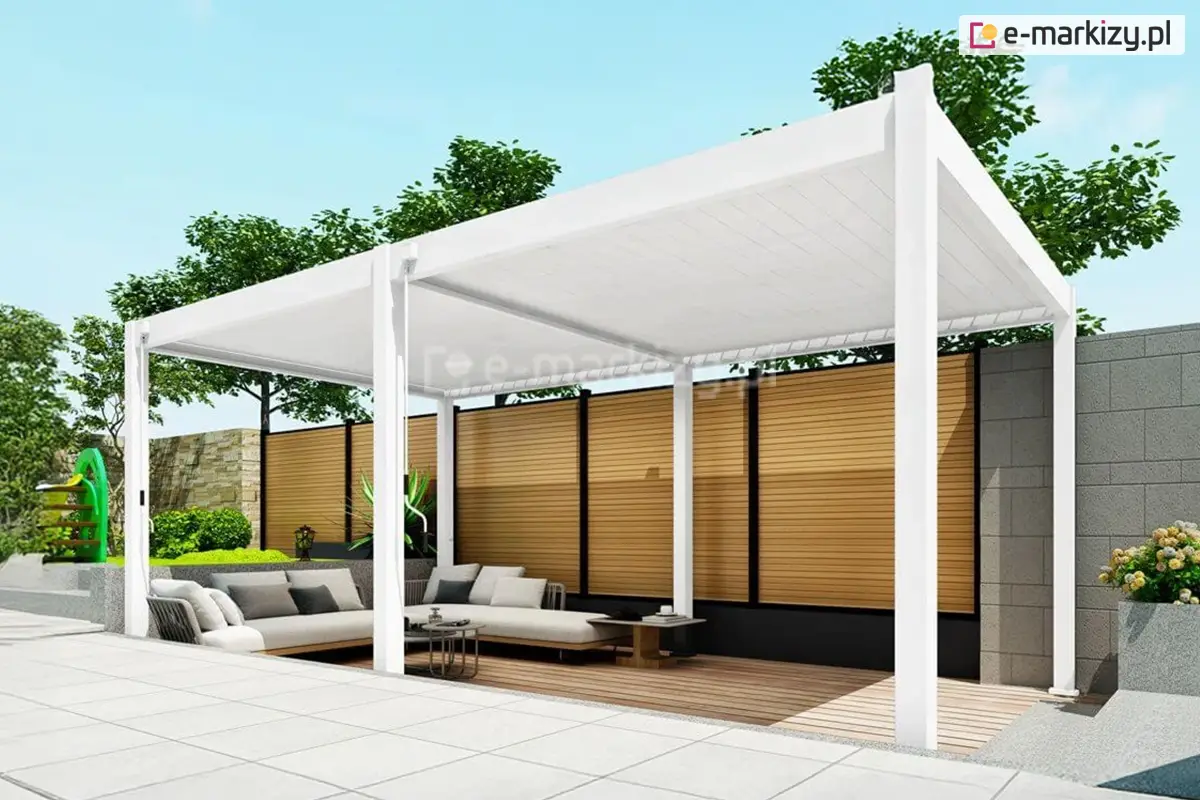 Nowoczesna biała pergola Marlo o szerokości 6 metrów przy żaluzjowym płocie w kolorze drewna. Zadaszenie ustawione na drewnianym podeście, wewnątrz wygodna narożna sofa i stoliki kawowe, tworzące przytulną strefę wypoczynkową.