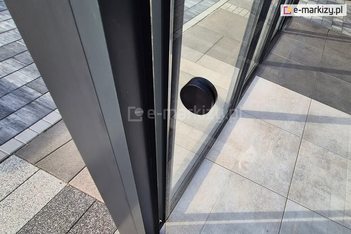 Bezramowe drzwi przesuwne Miros z paneli szklanych, montowane w nowoczesnej pergoli – minimalistyczna konstrukcja idealna do zabudowy tarasu.