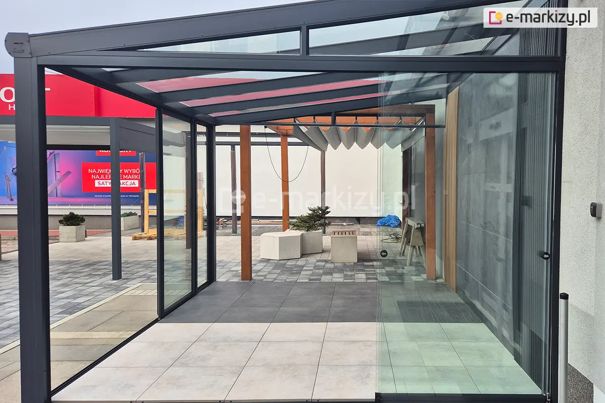 Drzwi przesuwne Miros zsunięte na bok, umożliwiające pełne otwarcie przestrzeni tarasu zabudowanego aluminiowym zadaszeniem ze szklanym dachem