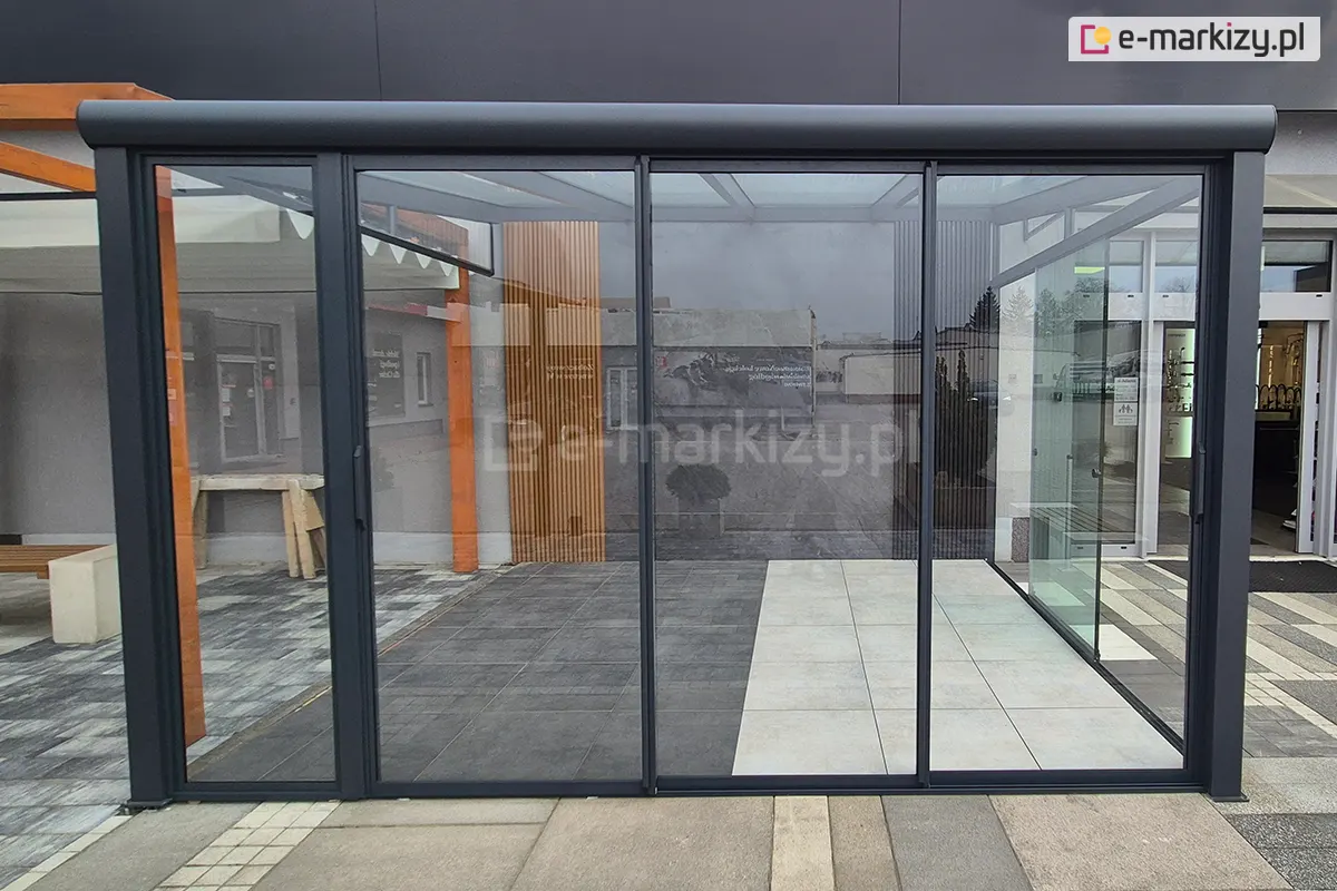 Zamknięte, przesuwne drzwi szklane Sotro z solidną, aluminiową ramą w kolorze antracytowym, przeznaczone do zadaszenia pergoli lub tarasu. Zdjęcie prezentuje elegancką i nowoczesną stylistykę konstrukcji.