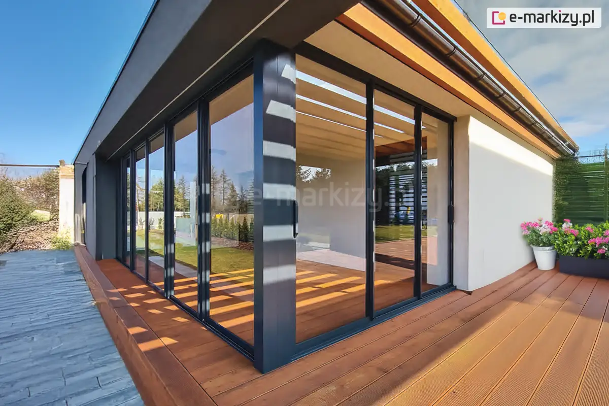 Przesuwne drzwi tarasowe Sotro z ramowymi panelami szklanymi w kolorze konstrukcji antracyt na dużym, drewnianym tarasie przy nowoczesnym domu