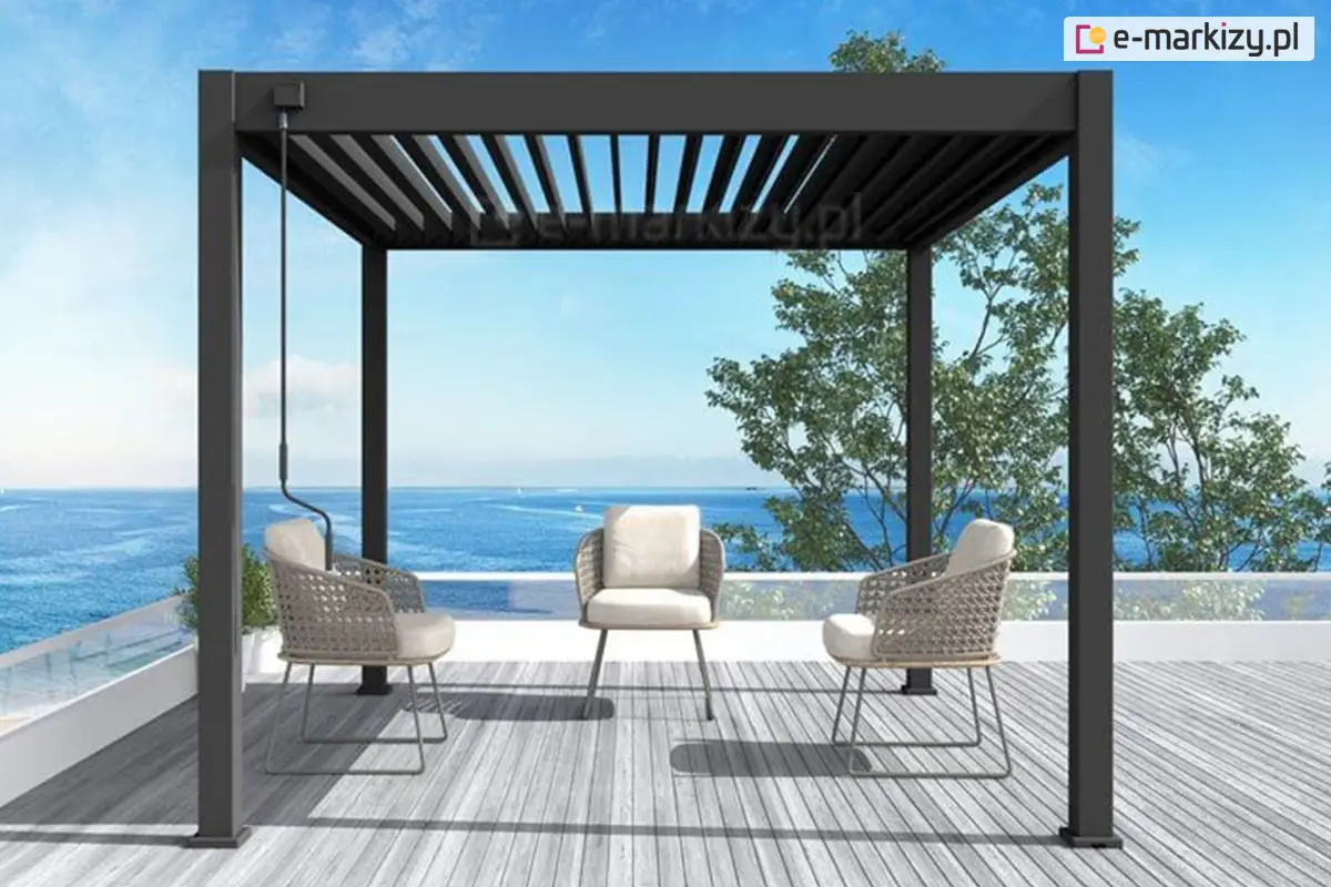Stylowa pergola Marlo z czarną aluminiową konstrukcją i ruchomym zadaszeniem lamelowym, ustawiona na tarasie z widokiem na morze. Wnętrze z trzema eleganckimi fotelami i miękkimi poduszkami tworzy idealną przestrzeń do relaksu na świeżym powietrzu z panoramicznym widokiem na wodę.