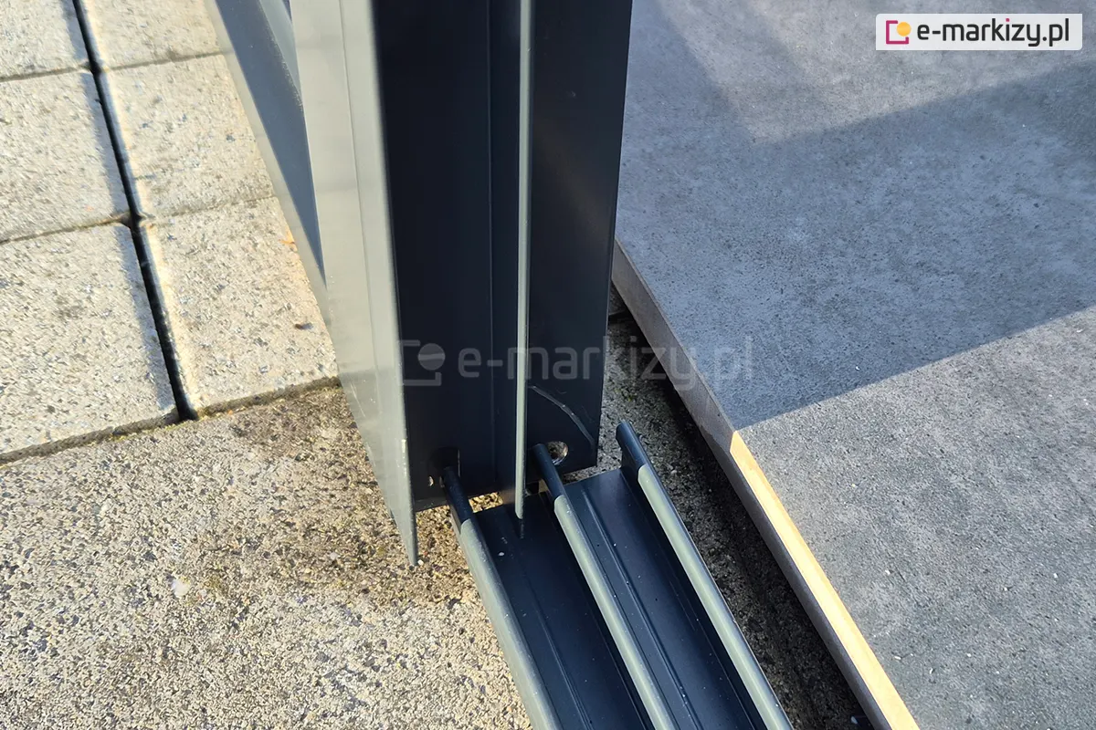 Zbliżenie na montaż prowadnicy systemu drzwi Sotro przykręconej bezpośrednio do aluminiowej podpory pergoli.