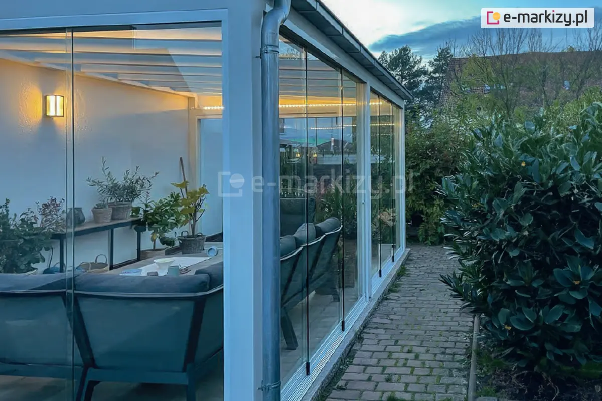 szklony ogród zimowy z systemem Miros o białej konstrukcji, oświetlony taśmami led, tworzący przytulną przestrzeń relaksu podczas pogodnego świtu