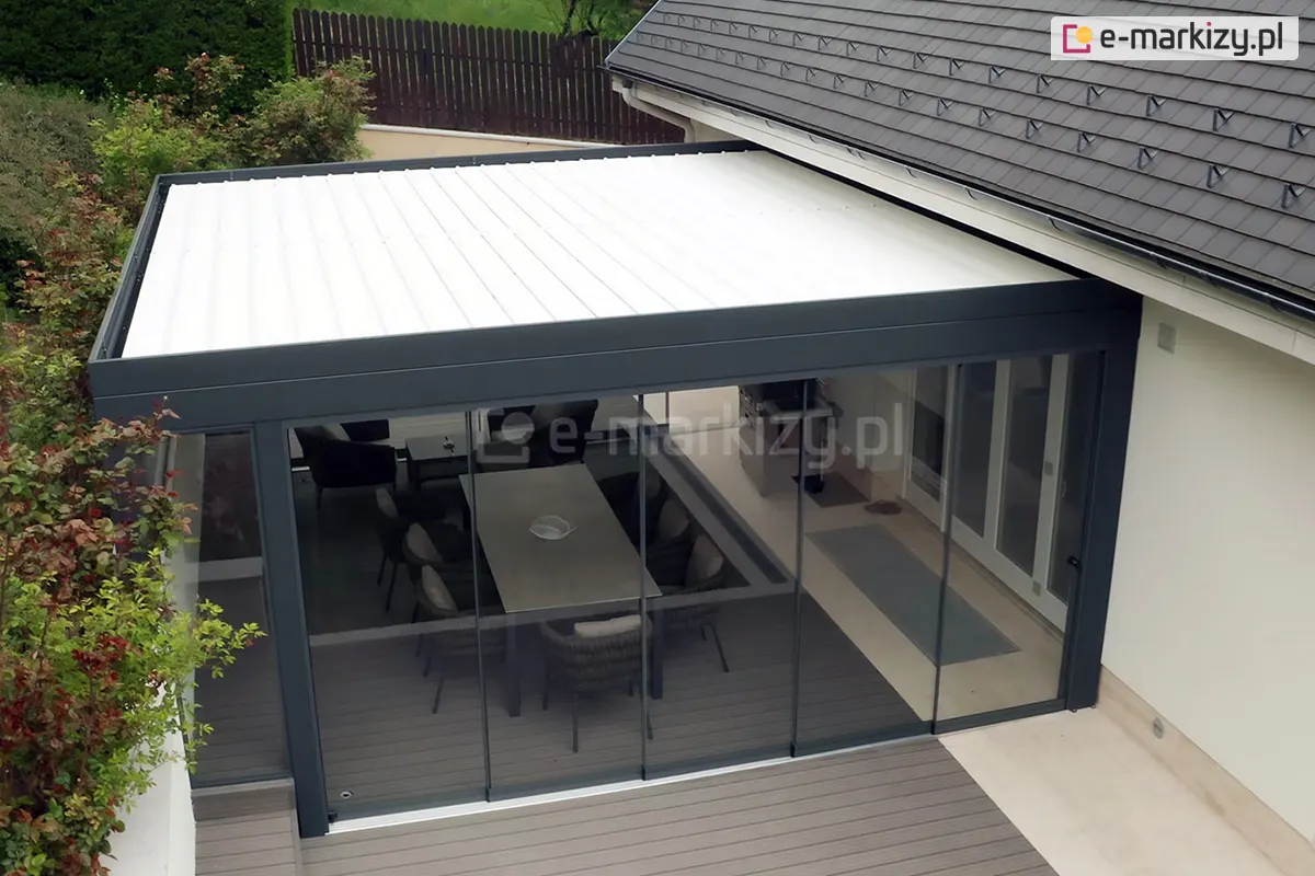 Pergola lamelowa z dachem z obracanymi lamelami, zabudowana pięcioma panelami szklanymi Miros w systemie bezramowym, tworząca komfortową przestrzeń tarasową