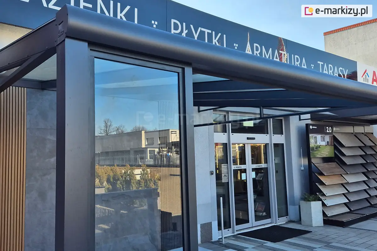 Nowoczesna pergola tarasowa prezentowana na ekspozycji sklepu, z aluminiową ścianką szklaną Fest — solidna konstrukcja z przeszkleniem dla eleganckiego osłonięcia wejścia