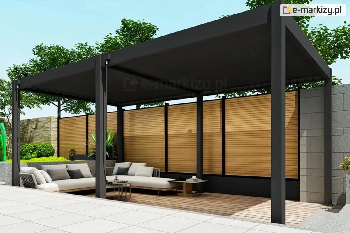Nowoczesna pergola Marlo w kolorze antracytowym, ustawiona na przestronnym tarasie wyłożonym jasnymi płytkami. Konstrukcja aluminiowa z lamelowym dachem osłania strefę wypoczynkową z narożną sofą i stolikami kawowymi. Tło stanowią dekoracyjne panele drewnopodobne i murki oporowe z betonu architektonicznego.