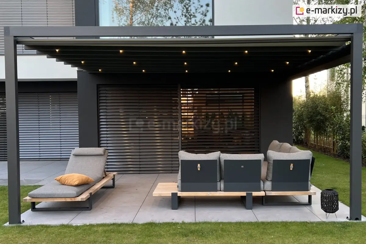 Nowoczesna pergola tarasowa Square Flat z zamkniętym dachem tkaninowym i włączonymi punktami świetlnymi LED, zamontowana przy elewacji domu z żaluzjami zewnętrznymi, wyposażona w designerskie meble ogrodowe i otoczona trawnikiem oraz roślinnością.