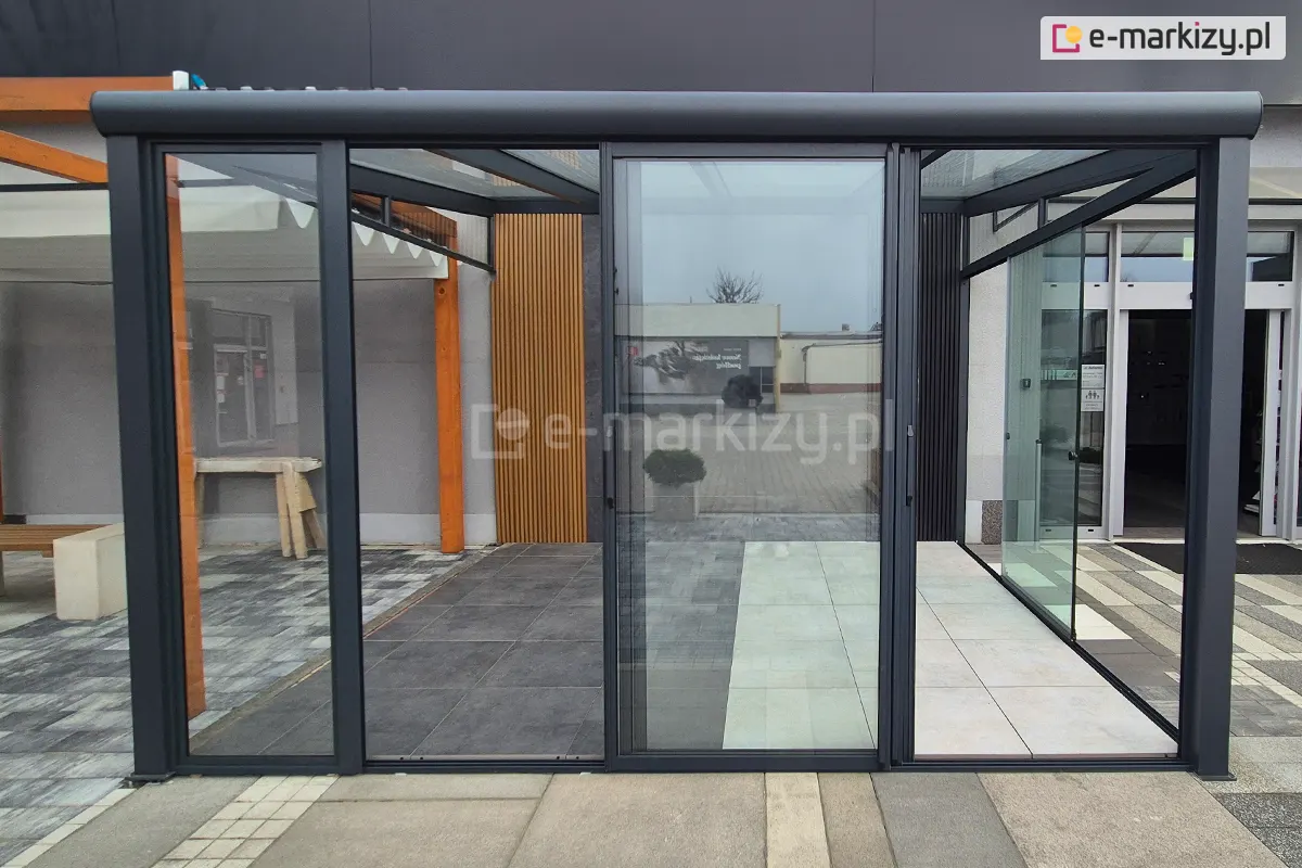 Szklane drzwi przesuwne Sotro w ciemnoszarej ramie aluminiowej, otwarte na boki z wszystkimi panelami zsuniętymi na środek konstrukcji. Konstrukcja systemu szklanego idealnie łączy funkcjonalność z minimalistycznym stylem.