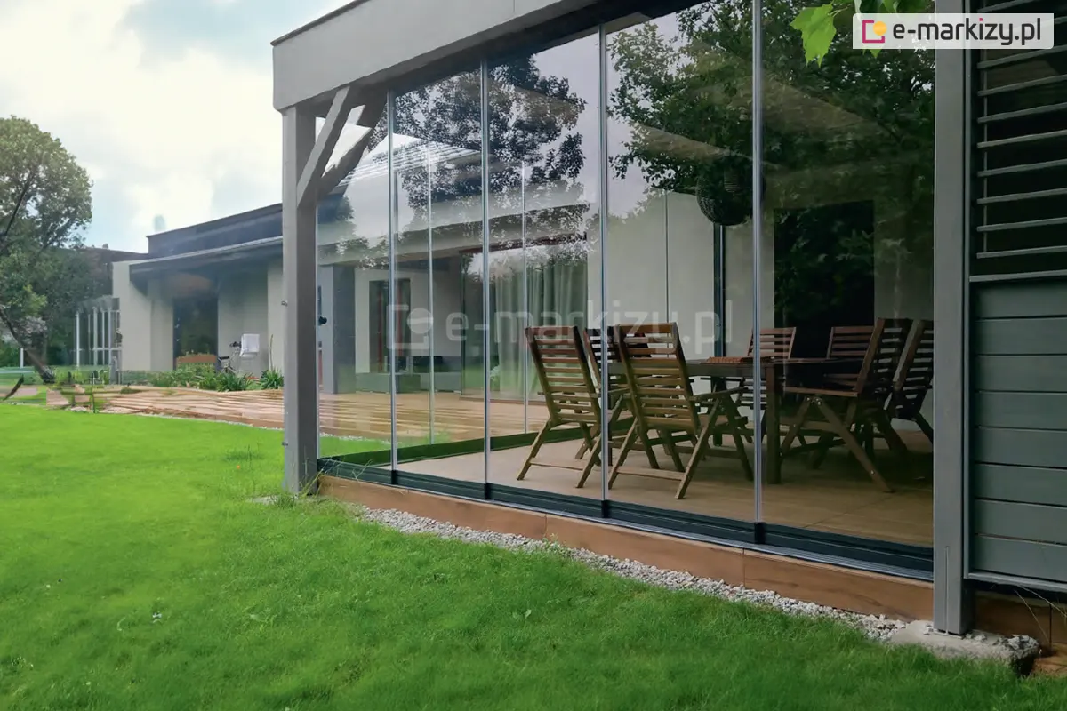 Tarasowe szklane drzwi przesuwne Miros zamontowane w eleganckiej konstrukcji ogrodowej, tworzące nowoczesną jadalnię na świeżym powietrzu z widokiem na ogród.