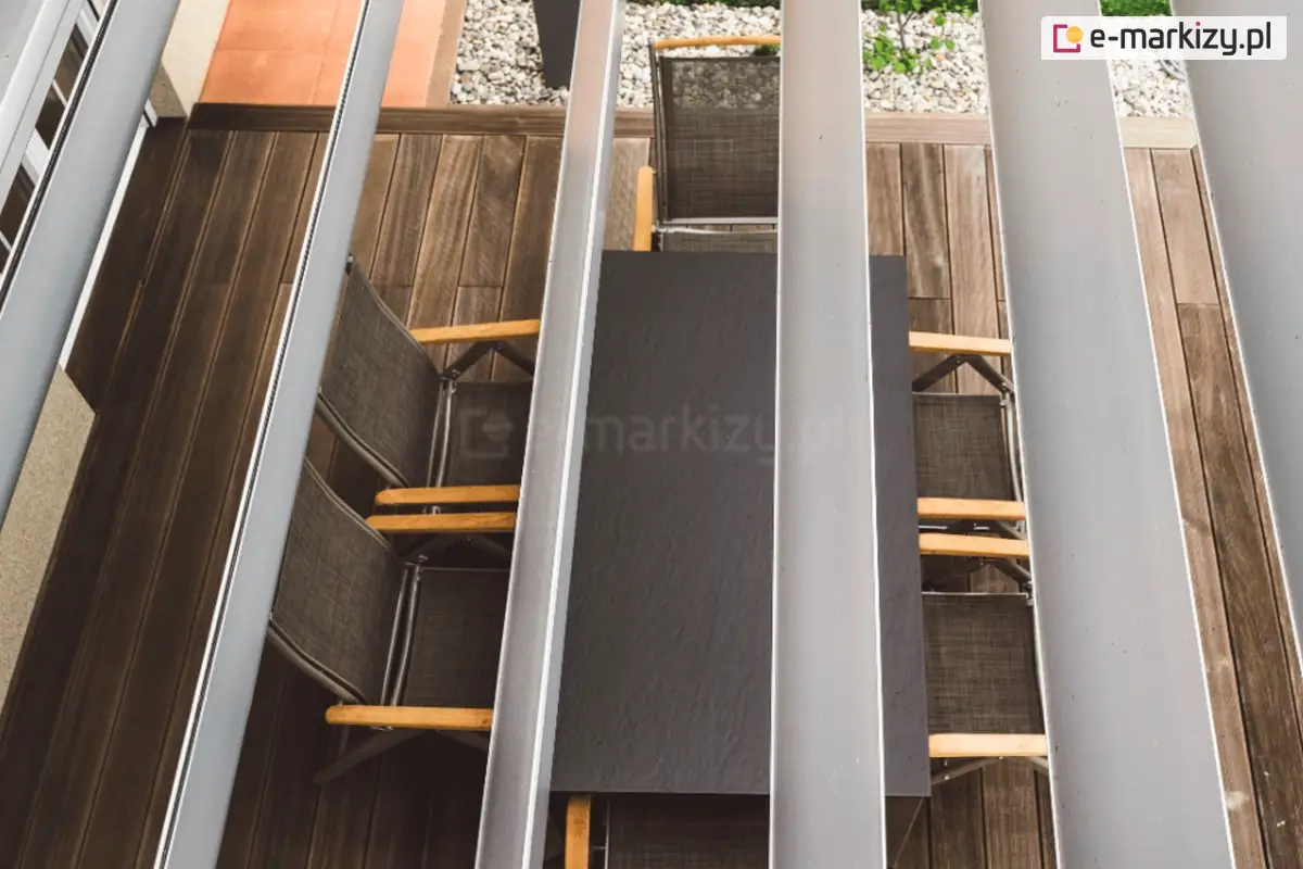 Widok z lotu ptaka na drewniany taras wyposażony w białą pergolę Gloria z półotwartymi lamelami dachowymi nad jadalnią na świeżym powietrzu