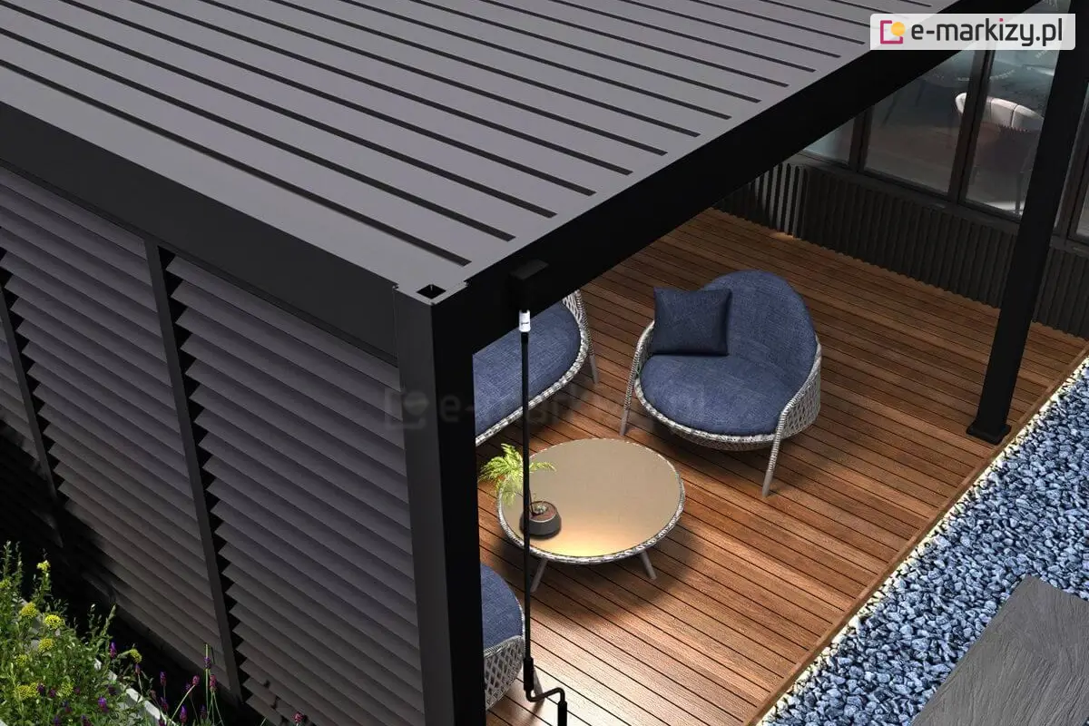 Nowoczesna pergola ogrodowa Marlo z zabudową żaluzjową po bokach, zapewniającą ochronę przed słońcem i prywatność. Konstrukcja wykonana z aluminium w kolorze antracytowym, osadzona na drewnianym tarasie. Pod pergolą znajdują się stylowe, okrągłe fotele z niebieskimi poduszkami oraz niski stolik kawowy, tworząc elegancką strefę relaksu na zewnątrz.